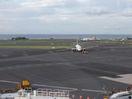 Mehrere Flugzeuge stehen am Flughafen auf dem Rollfeld in Küstennähe mit Blick auf das Meer im Hintergrund.