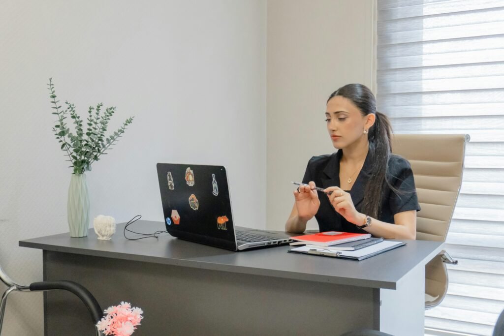 Frau sitzt an einem Schreibtisch und arbeitet an einem Laptop in einem gut beleuchteten Raum