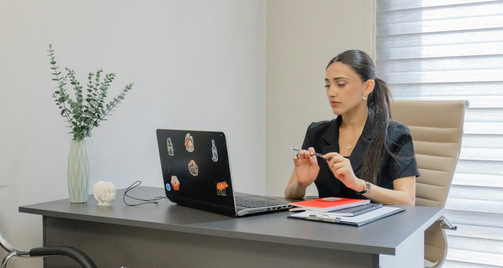 Frau sitzt an einem Schreibtisch und arbeitet an einem Laptop in einem gut beleuchteten Raum