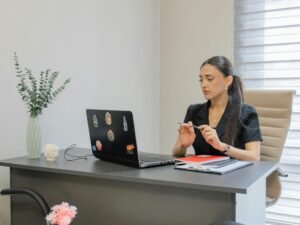 Frau sitzt an einem Schreibtisch und arbeitet an einem Laptop in einem gut beleuchteten Raum