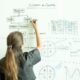 Frau zeichnet ein Flussdiagramm mit Markern auf ein Whiteboard zur Visualisierung von Arbeitsprozessen.