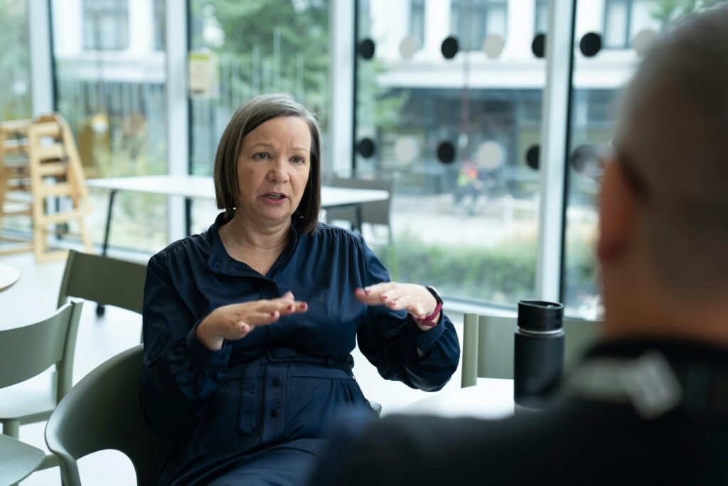 Frau erklärt Ideen mit Gesten, während sie mit einer Person in einem modernen Büro spricht