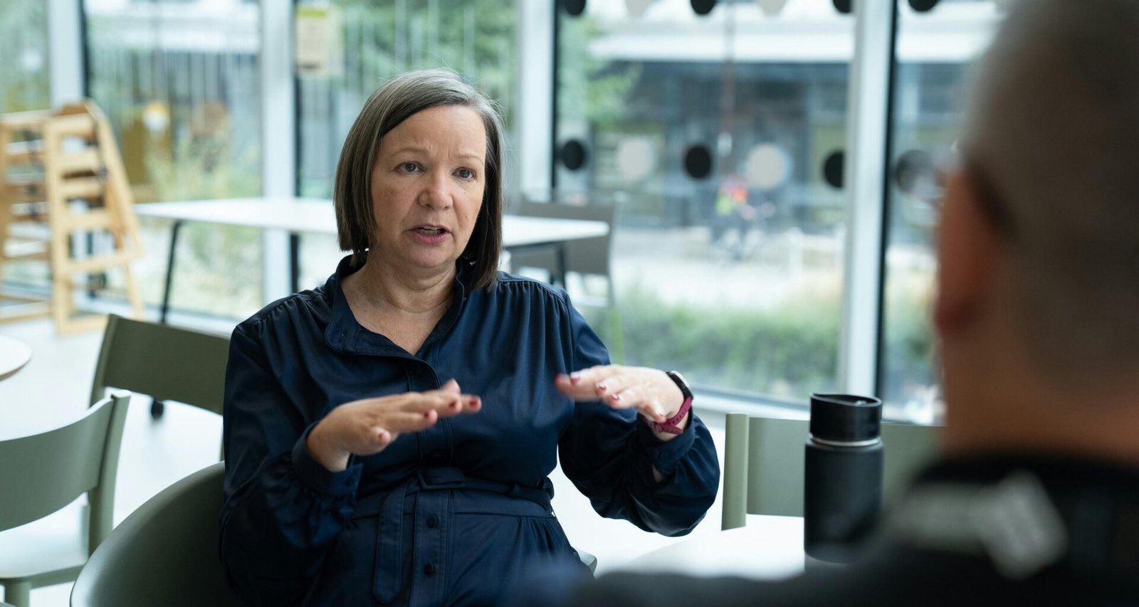 Frau erklärt Ideen mit Gesten, während sie mit einer Person in einem modernen Büro spricht