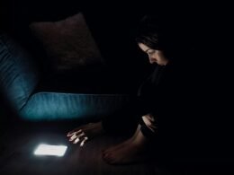 Frau im schwarzen Langarmshirt sitzt auf einem blauen Sofa, modernes Wohnzimmer mit urbanem Stil