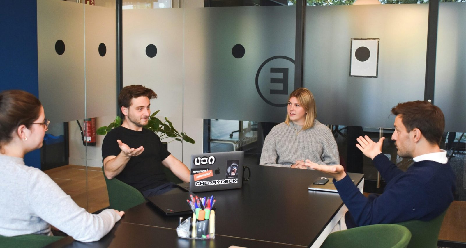 Zwei Frauen sitzen nebeneinander an einem Tisch und arbeiten gemeinsam mit Laptops in einem modernen Büro