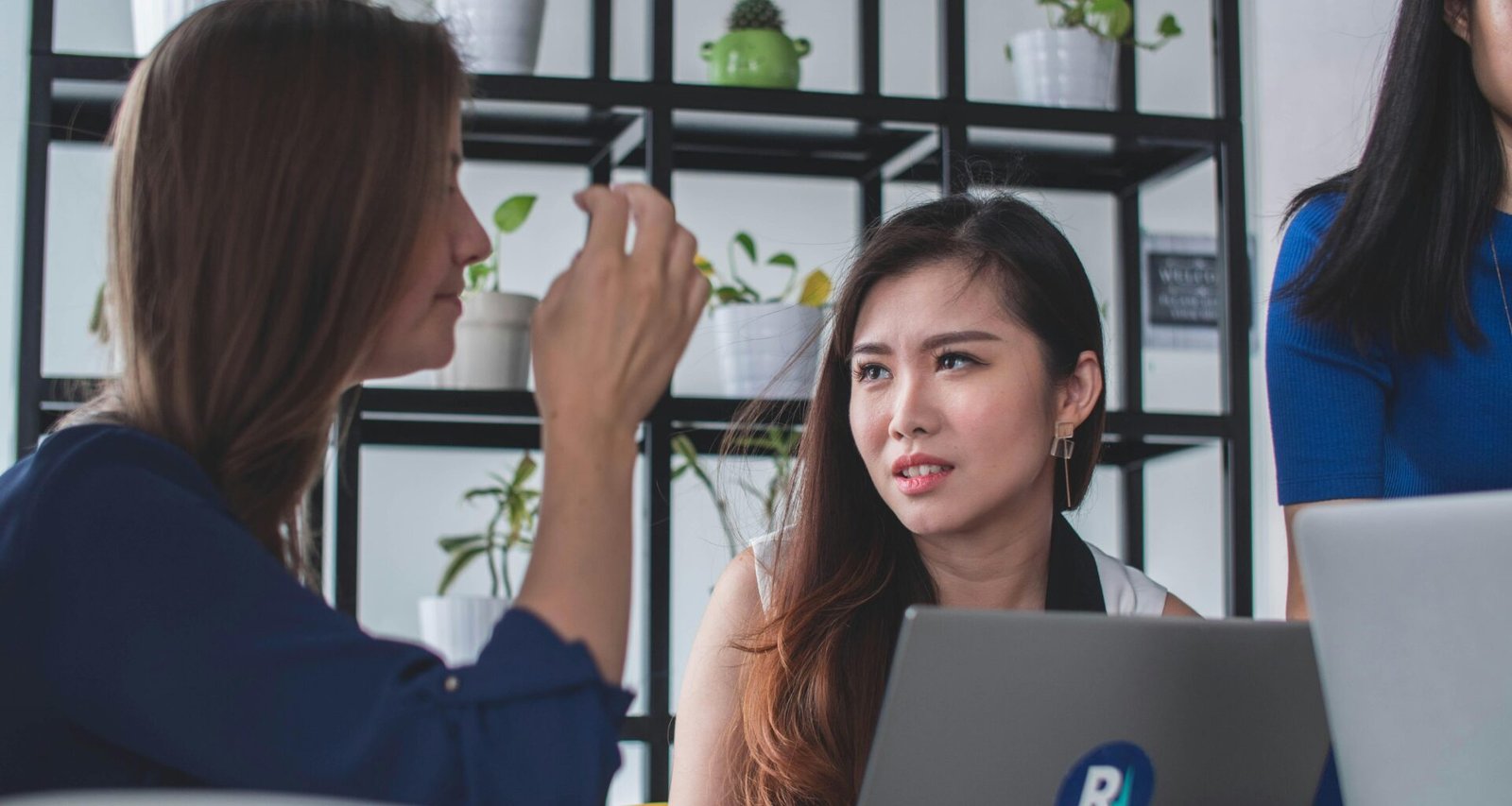 Frau sitzt an einem Tisch vor einem Laptop und arbeitet konzentriert im digitalen Umfeld