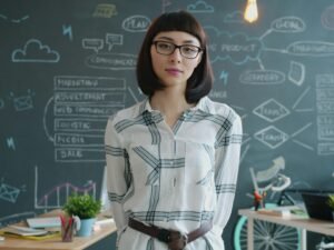 Frau steht vor einer Kreidetafel mit grafischen Diagrammen und erklärt Inhalte, Fokus auf Wissenstransfer und Präsentation