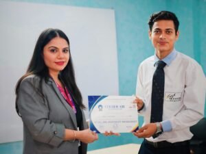 Frau übergibt im Büro einem Mann ein Zertifikat, beide stehen an einem Schreibtisch und wirken professionell