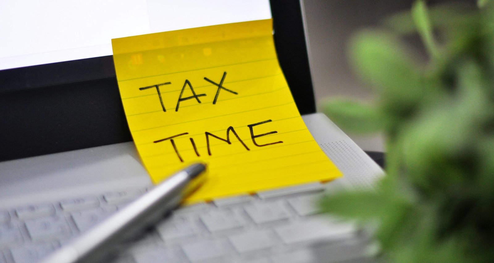 Gelber Haftzettel mit dem handschriftlichen Hinweis 'Tax Time' als Symbol für Steuertermine und Abgabefristen.