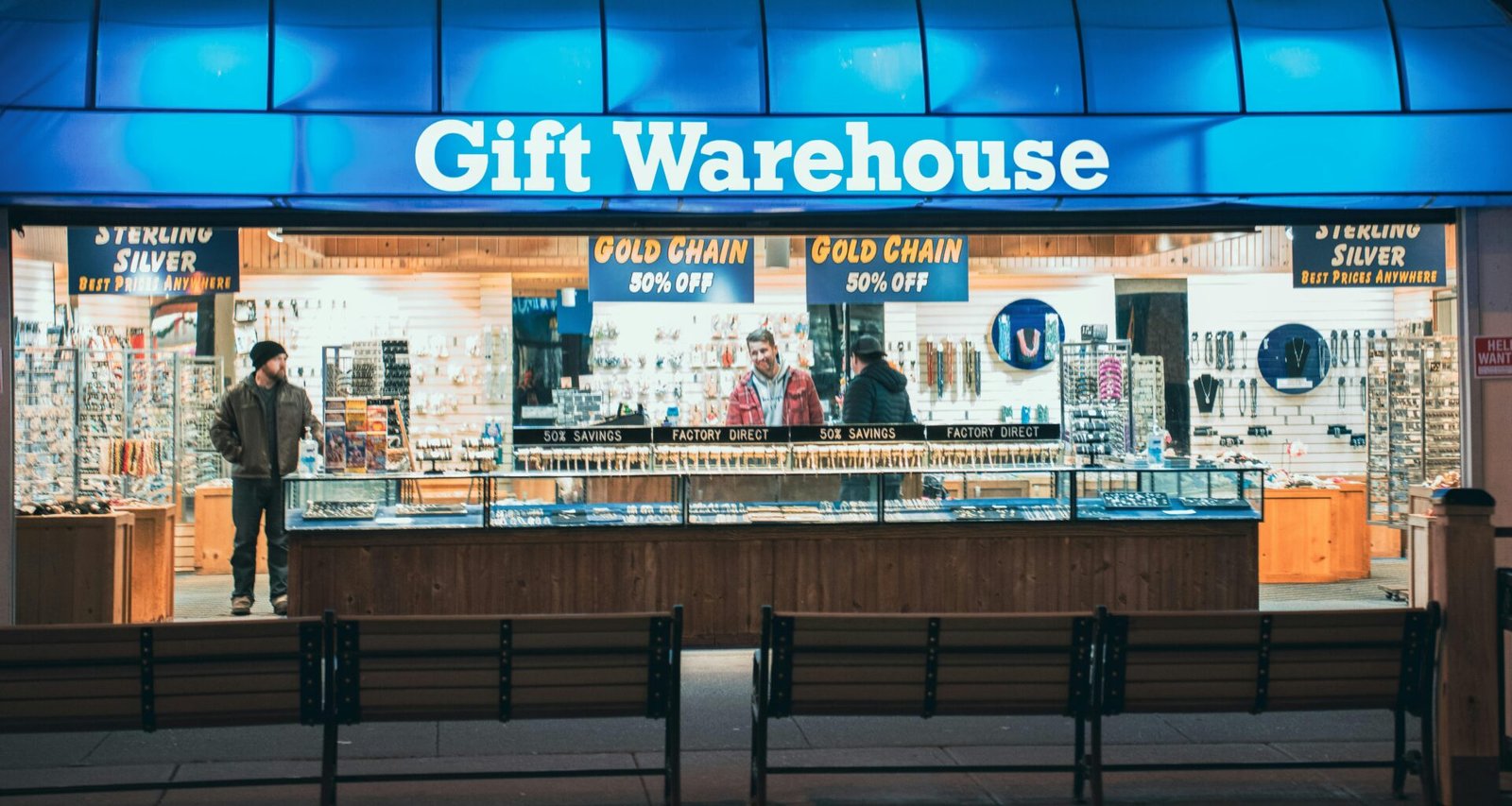 Nachtszene in einem Geschenkewarenlager, mehrere Personen kaufen zwischen Regalen und bunten Produkten ein