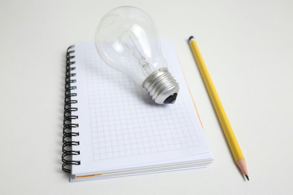 Eine Glühbirne und ein Bleistift liegen nebeneinander auf einem Notizblock, fotografiert für einen Technik-Artikel.