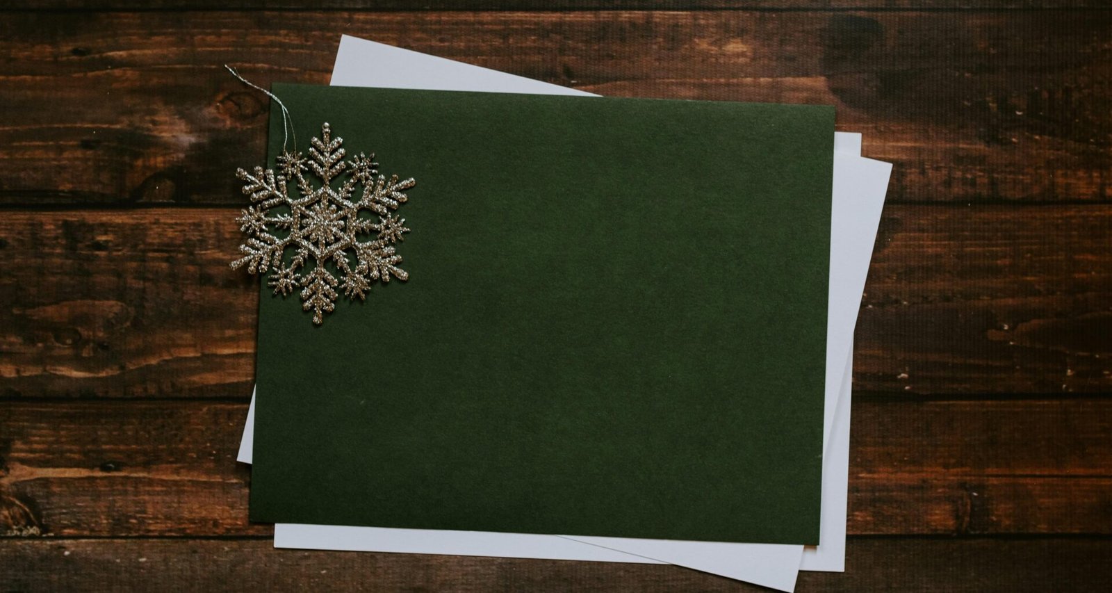 Graue Schneeflocke aus Papier auf grünem Untergrund, fotografiert als Nahaufnahme mit Fokus auf Struktur und Muster.