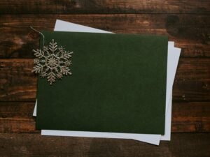 Graue Schneeflocke aus Papier auf grünem Untergrund, fotografiert als Nahaufnahme mit Fokus auf Struktur und Muster.