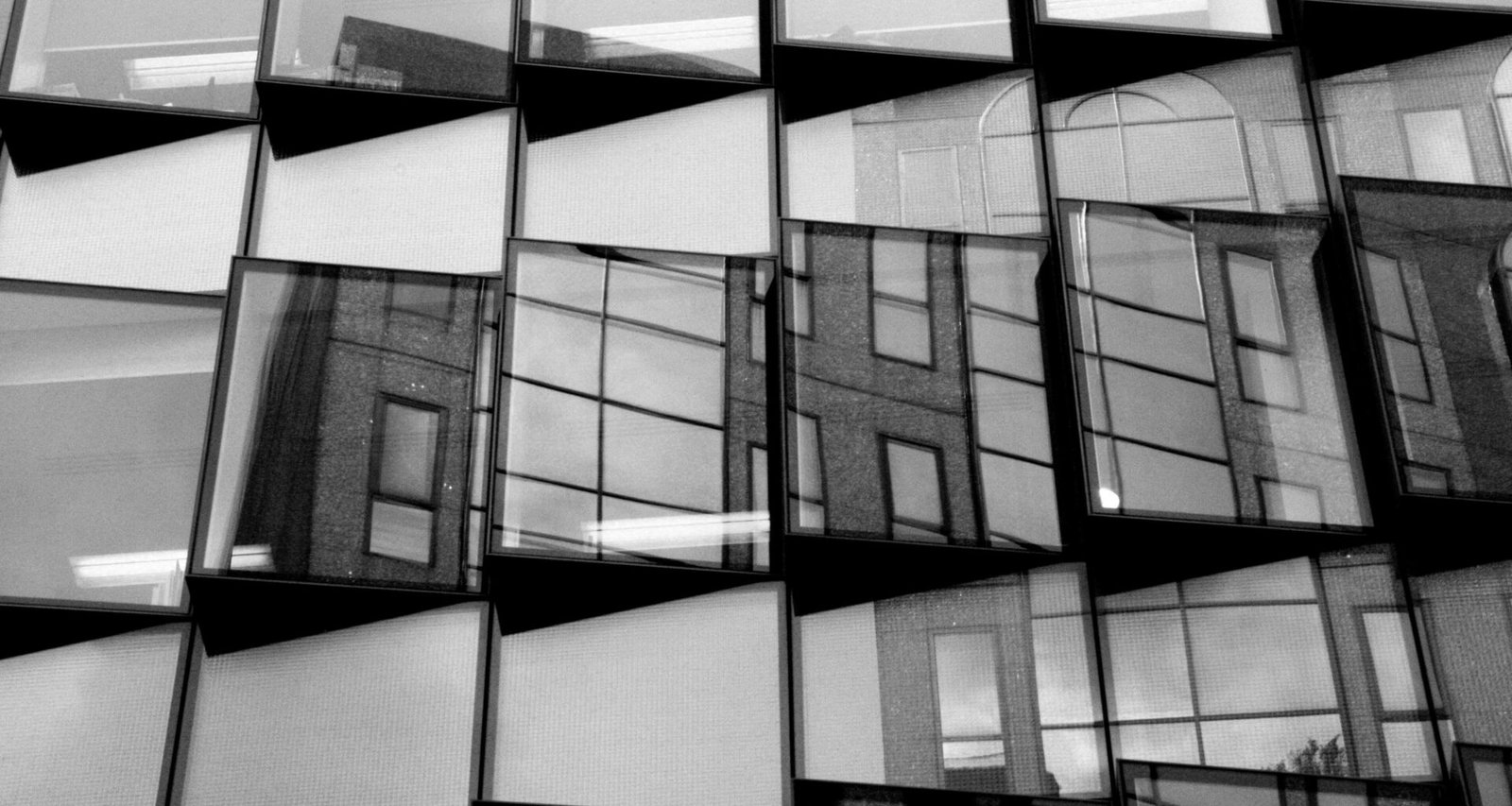 Schwarzweißfoto eines Fensters mit klaren Linien und moderner Architektur, fotografiert aus einem interessanten Blickwinkel