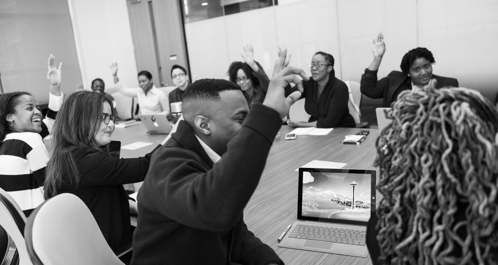 Schwarzweißfoto von mehreren Personen in einem Arbeitsraum, die an einem Tisch gemeinsam arbeiten