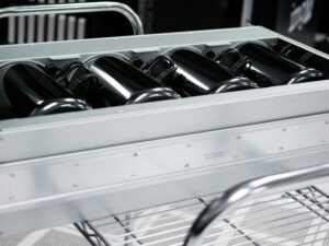 Graues, rechteckiges Etui in Schwarzweißaufnahme auf einem Drahtregal – modernes, schlichtes Design im Fokus