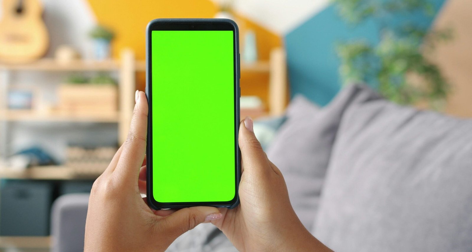 Nahaufnahme von Händen, die ein Smartphone mit grünem Display halten, geeignet für digitale Präsentationen