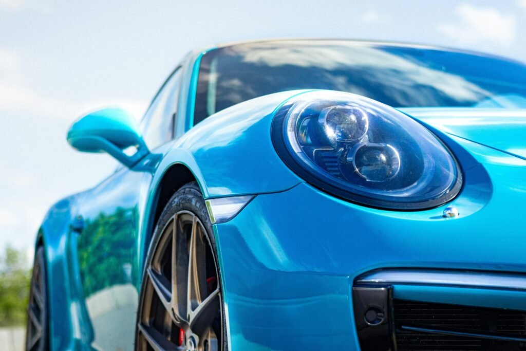 Ein blauer Sportwagen reflektiert Sonnenlicht und steht frei im Freien, Karosserie und Details sind gut sichtbar