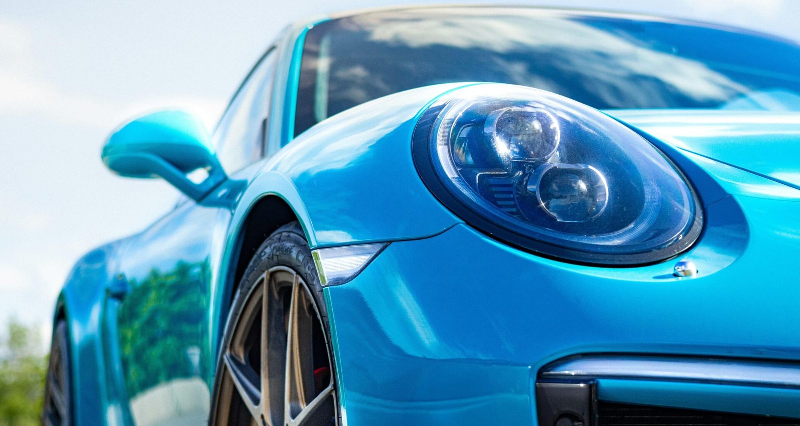 Ein blauer Sportwagen reflektiert Sonnenlicht und steht frei im Freien, Karosserie und Details sind gut sichtbar