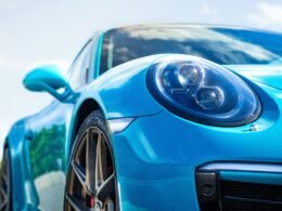 Ein blauer Sportwagen reflektiert Sonnenlicht und steht frei im Freien, Karosserie und Details sind gut sichtbar