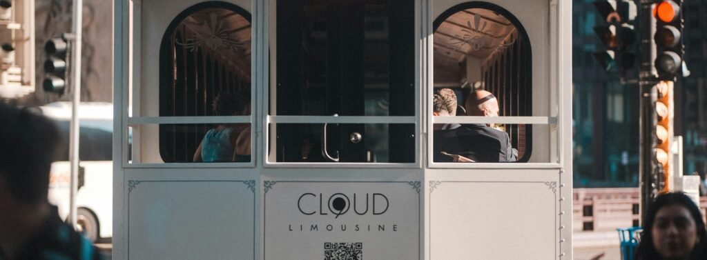 Menschen sitzen und stehen in einer fahrenden Straßenbahn im Stadtzentrum, Tageslicht fällt durch die Fenster.