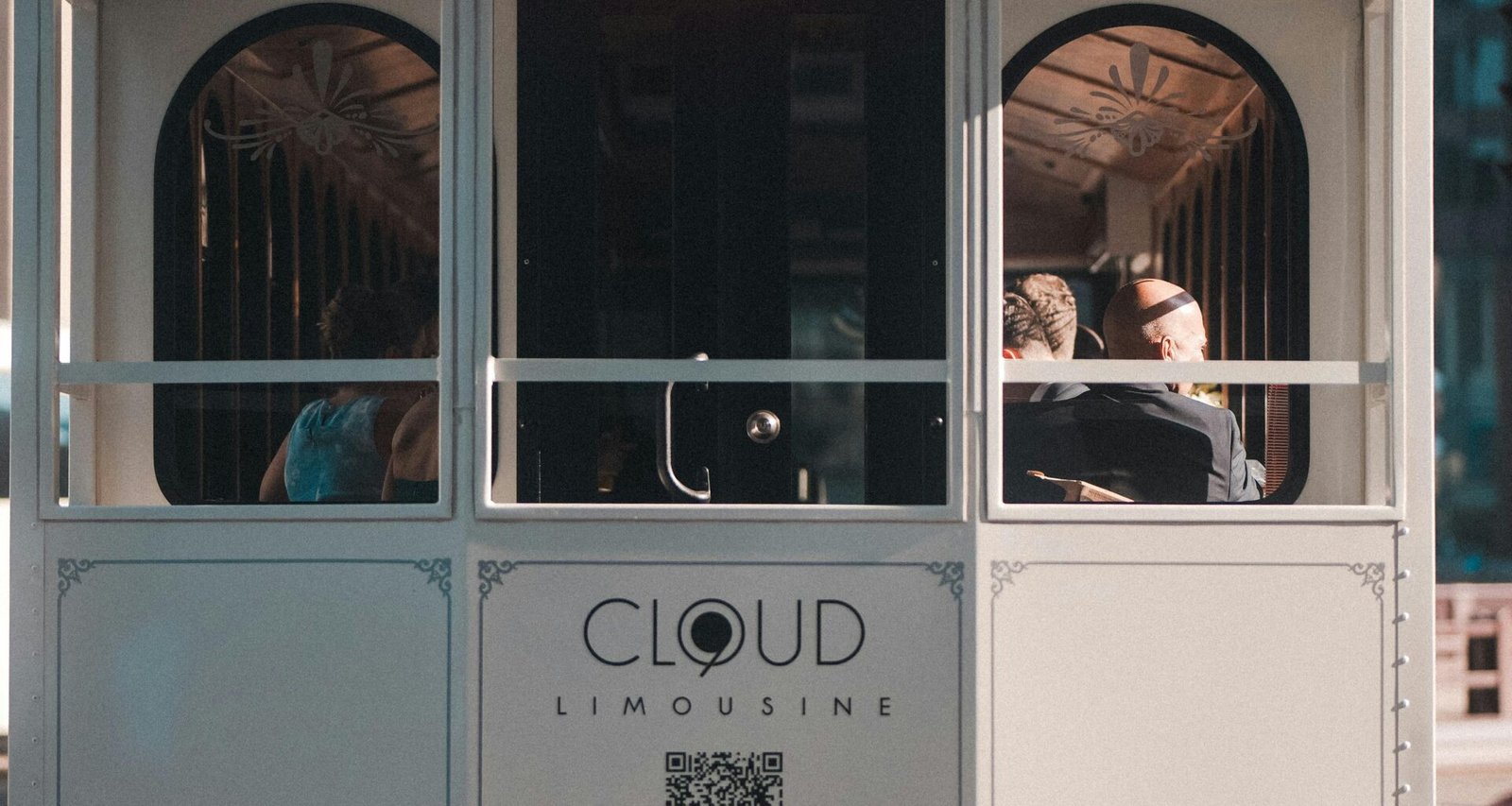 Menschen sitzen und stehen in einer fahrenden Straßenbahn im Stadtzentrum, Tageslicht fällt durch die Fenster.