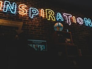 Leuchtendes Neon-Schild mit dem Schriftzug Inspiration, aufgenommen in urbaner Umgebung, von Jonathan Kemper