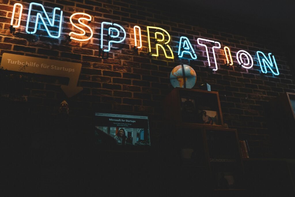 Neonschild mit dem Wort Inspiration leuchtet vor dunklem Hintergrund, modernes Design, fotografiert von Jonathan Kemper