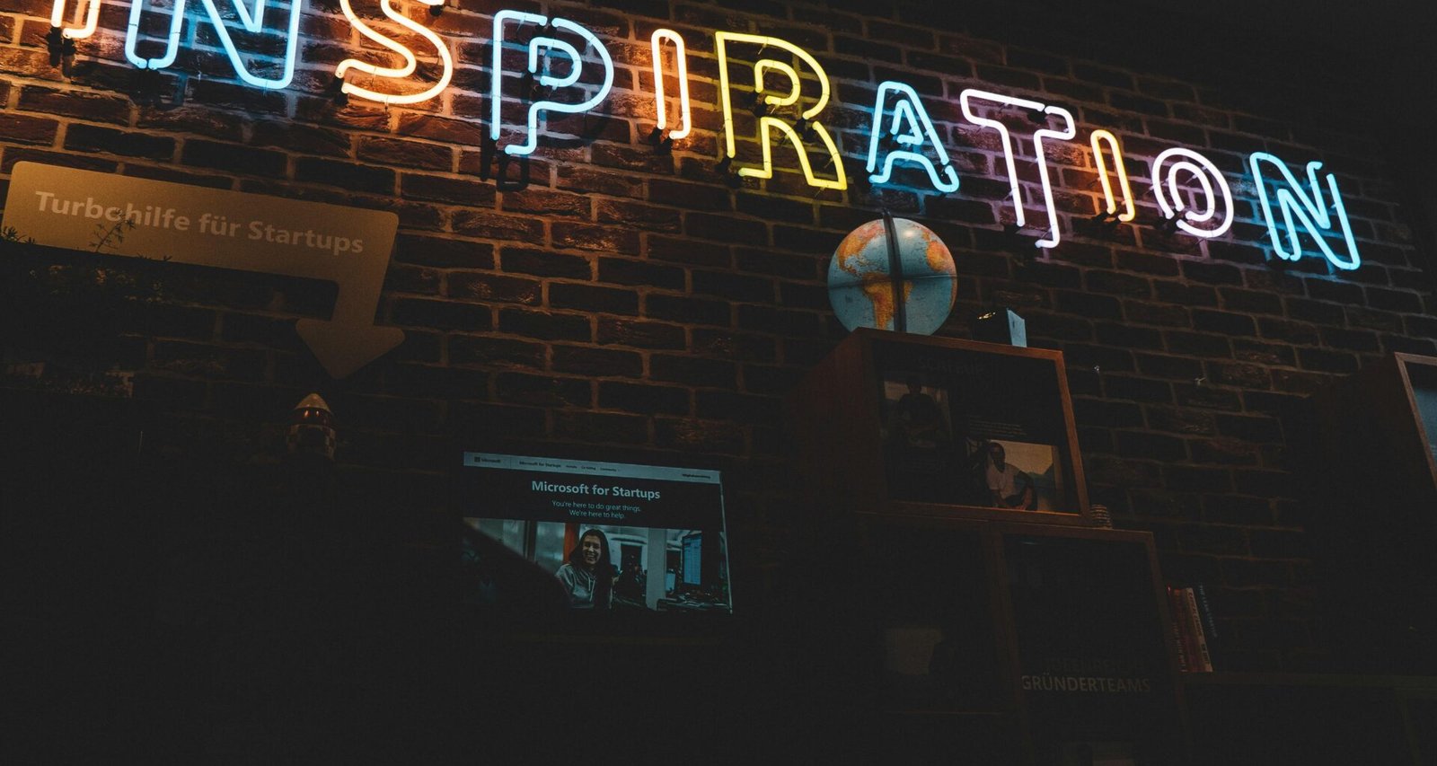 Neonschild mit dem Wort Inspiration leuchtet vor dunklem Hintergrund, modernes Design, fotografiert von Jonathan Kemper