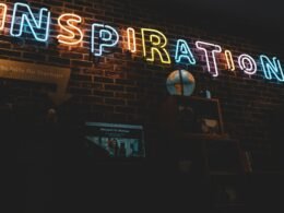 Neonschild mit dem Wort Inspiration leuchtet vor dunklem Hintergrund, modernes Design, fotografiert von Jonathan Kemper