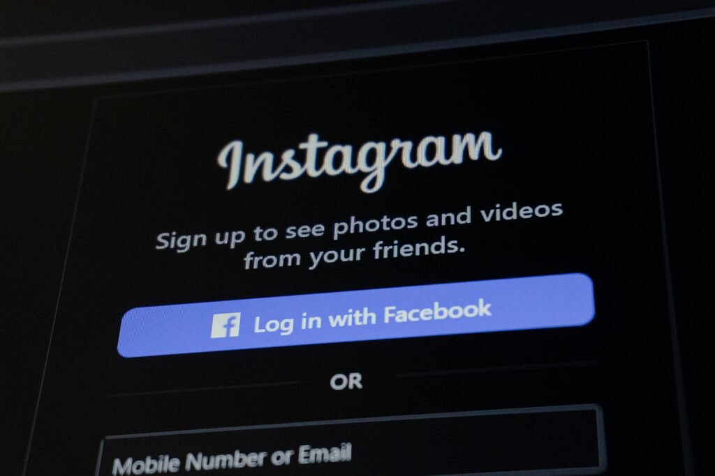 Smartphone zeigt Instagram-Anmeldebildschirm mit Facebook-Login-Option auf weißem Hintergrund.