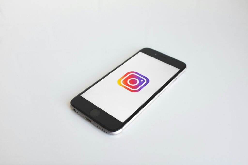 Instagram-Logo angezeigt auf einem space gray iPhone 6, fotografiert auf einem neutralen Hintergrund, Fokus auf App-Icon