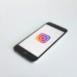 Instagram-Logo angezeigt auf einem space gray iPhone 6, fotografiert auf einem neutralen Hintergrund, Fokus auf App-Icon