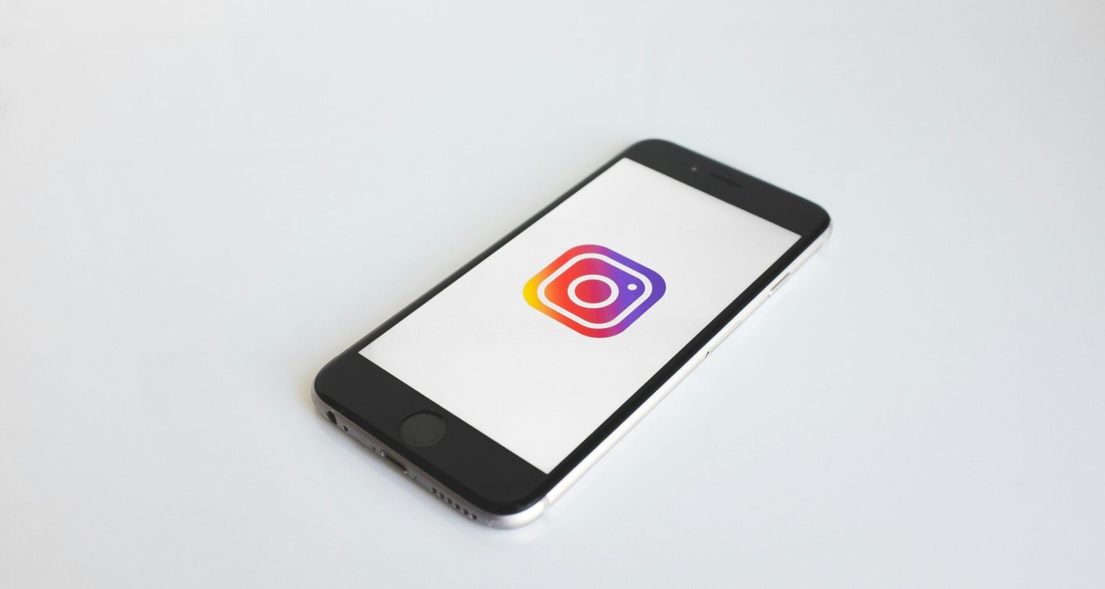 Instagram-Logo angezeigt auf einem space gray iPhone 6, fotografiert auf einem neutralen Hintergrund, Fokus auf App-Icon