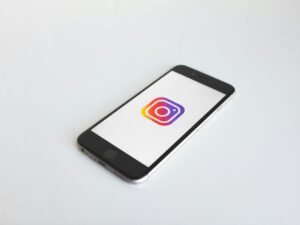 Instagram-Logo angezeigt auf einem space gray iPhone 6, fotografiert auf einem neutralen Hintergrund, Fokus auf App-Icon