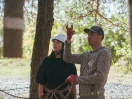 Eine Instruktorin zeigt einer jungen Frau bei einer Outdoor-Aktivität wichtige Techniken und Sicherheitsaspekte.