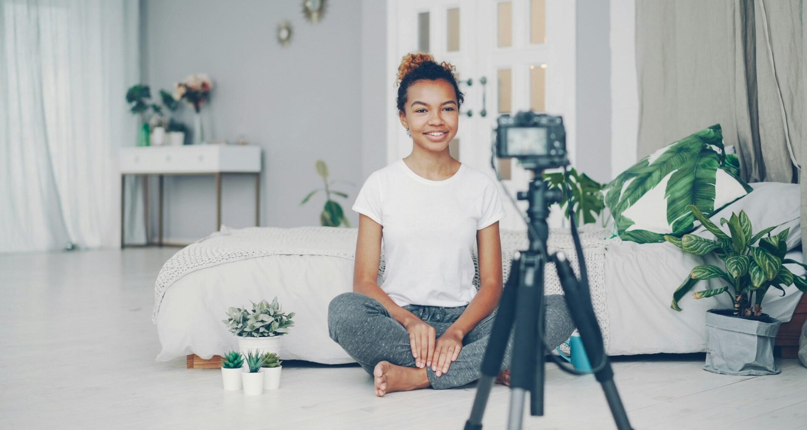 Junge Frau sitzt auf dem Boden und filmt mit einer digitalen Kamera für kreative Projekte in Innenraum