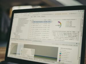 Geöffneter Laptop mit sichtbar angezeigtem Programmiercode und mehreren Datencharts auf dem Bildschirm in moderner Arbeitsumgebung