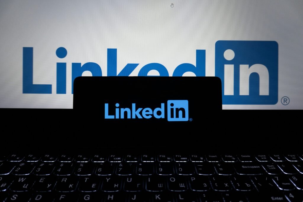 Das LinkedIn-Logo ist auf dem Bildschirm eines Smartphones und eines Laptops gleichzeitig zu sehen.