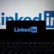 Das LinkedIn-Logo ist auf dem Bildschirm eines Smartphones und eines Laptops gleichzeitig zu sehen.