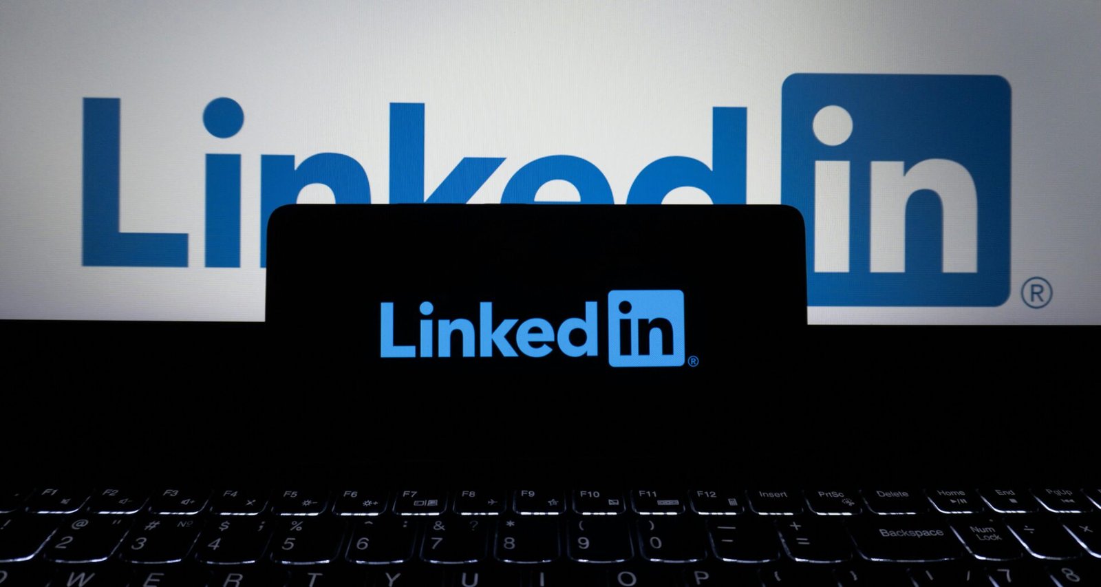Das LinkedIn-Logo ist auf dem Bildschirm eines Smartphones und eines Laptops gleichzeitig zu sehen.