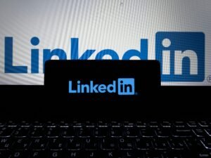 Das LinkedIn-Logo ist auf dem Bildschirm eines Smartphones und eines Laptops gleichzeitig zu sehen.