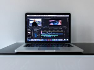 MacBook Pro steht auf einem schwarzen Schreibtisch, minimalistisches Arbeitsumfeld mit moderner Technologie und klarer Linienführung