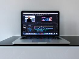 Ein MacBook Pro auf einem schwarzen Schreibtisch, geeignet als Symbolbild für Technologie- und Bürothemen.