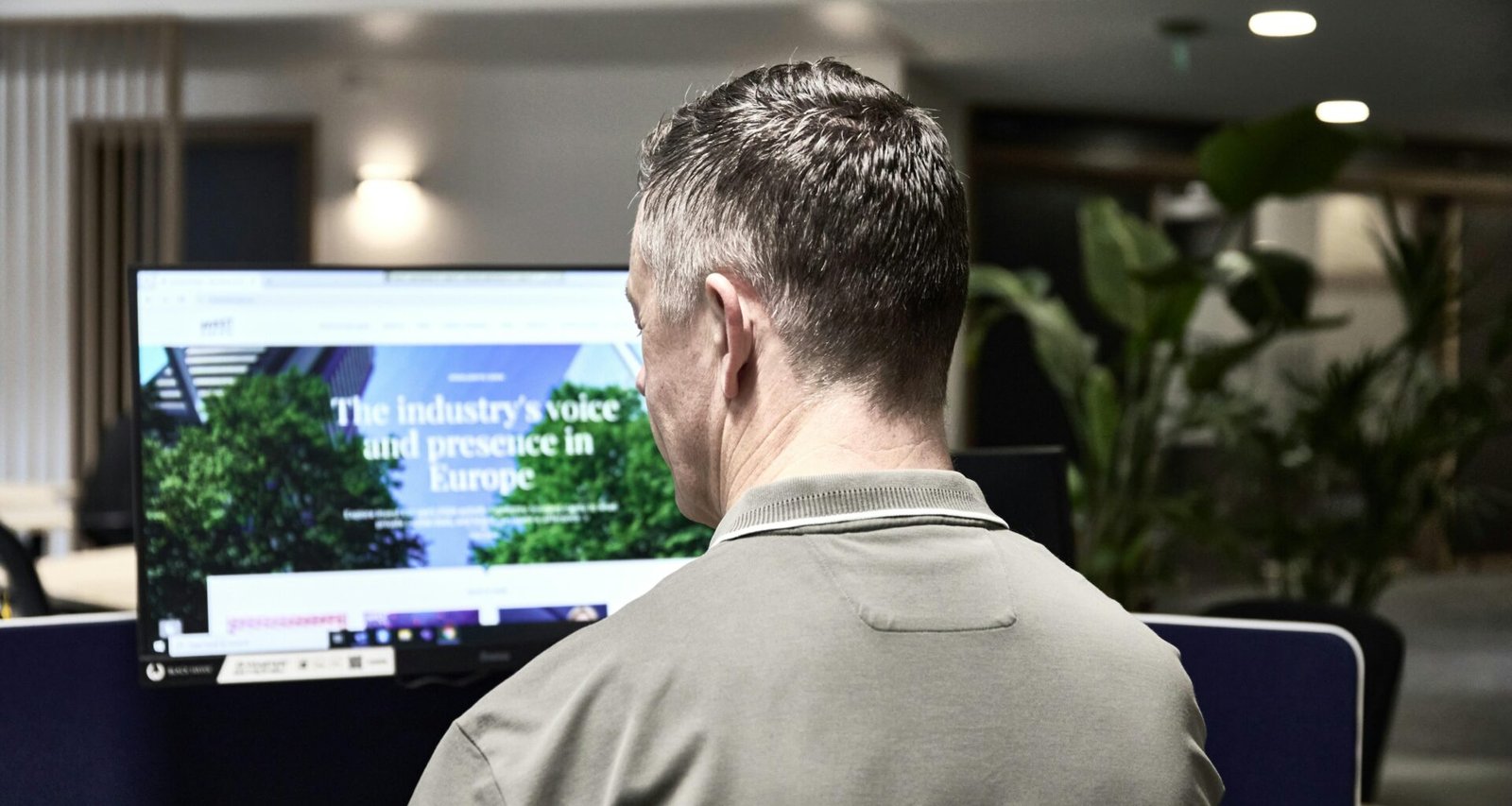 Mann arbeitet an einem Computer in einem modernen Büro, Schreibtisch mit Monitor und Büroausstattung