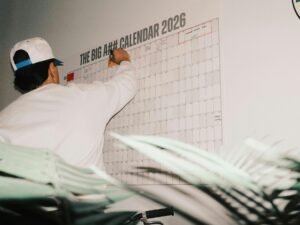 Ein Mann trägt mit Stift Einträge in einen großen Kalender für das Jahr 2026 ein