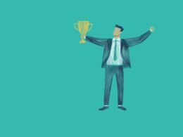 Ein Mann im Anzug steht mit erhobenen Armen und hält eine Trophäe; Gewinner eines Business- oder Marketing-Preises.