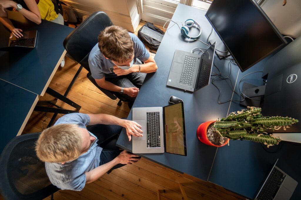 Ein Mann in grauem Langarmshirt arbeitet konzentriert an einem MacBook Pro an einem modernen Arbeitsplatz.