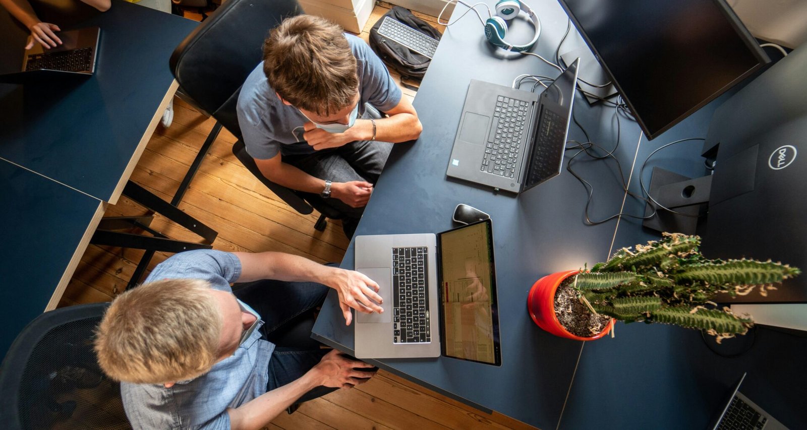 Ein Mann in grauem Langarmshirt arbeitet konzentriert an einem MacBook Pro an einem modernen Arbeitsplatz.