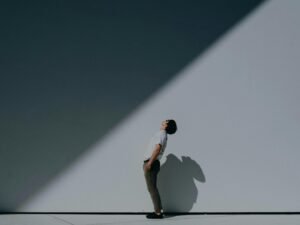 Mann in weißem T-Shirt und Shorts steht entspannt vor einer weißen Wand im Tageslicht